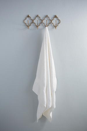 White towel hanging on hook against wallの写真素材
