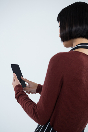 Rear view of waitress using mobile phone against white backgroundの写真素材