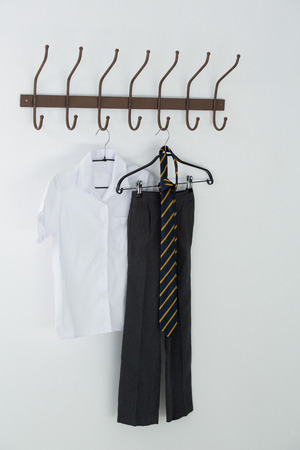 Formal shirt, tie and pants hanging on hook against white wallの写真素材