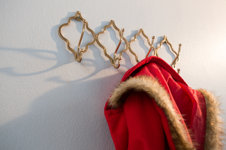 Close-up of red hoodie hanging on hook against white backgroundの写真素材