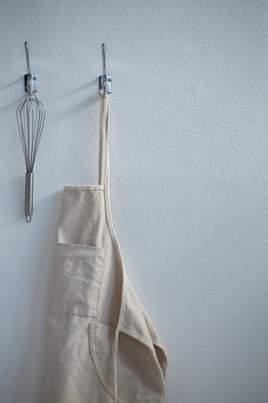 Close-up of apron and whisker hanging on hookの写真素材