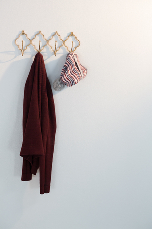 Warm clothes hanging on hook against white wallの写真素材