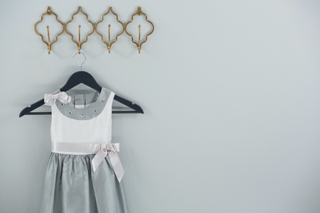 Dress hanging on hook against white wallの写真素材