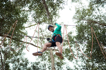 Happy man enjoying zip line adventure in park