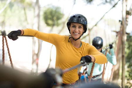 Happy woman enjoying zip line adventure in parkの写真素材