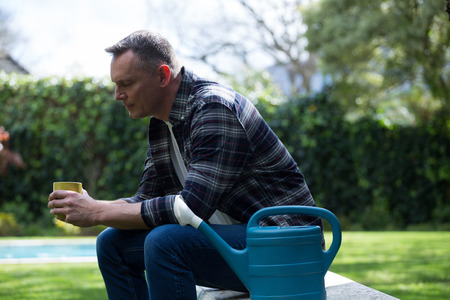Thoughtful man having cup of coffee in garden on a sunny dayの写真素材
