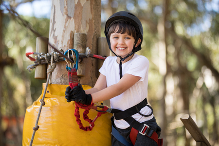 Smiling cute boy enjoying zip line adventure on sunny dayの写真素材