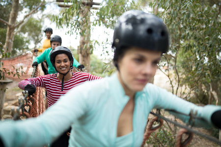 Smiling friends walking on rope bridgeの写真素材