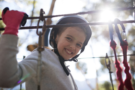 Smiling cute girl enjoying zip line adventure on sunny dayの写真素材