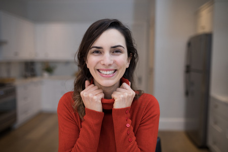 Portrait of happy woman sitting in kitchenの写真素材