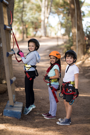 Portrait of happy kids preparing for zip line on a sunny dayの写真素材