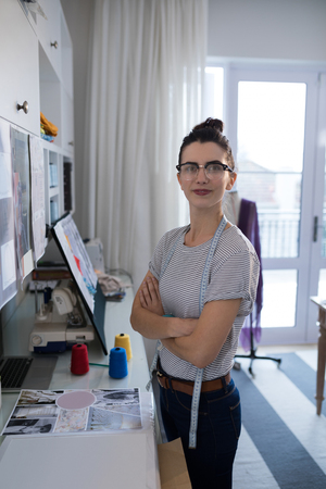Portrait of female designer standing with arms crossed at tableの写真素材