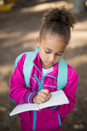 Close-up of girl writing in book at parkの写真素材