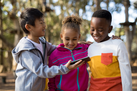 Kids reviewing pictures on mobile phone in park