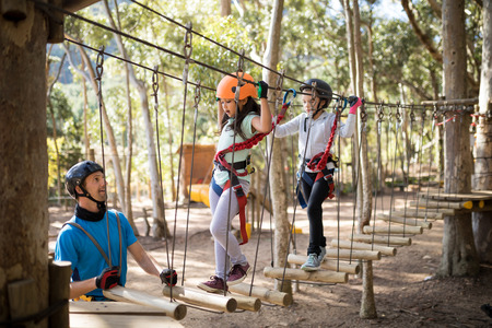 Instructor assisting kid in zip line on a sunny dayの写真素材