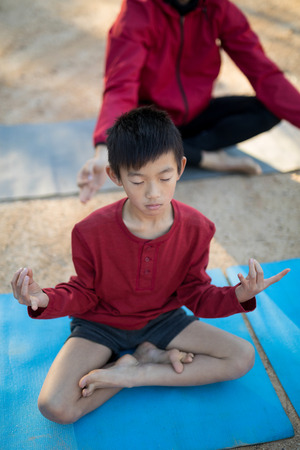 Overhead of boy meditating in park on a sunny dayの写真素材