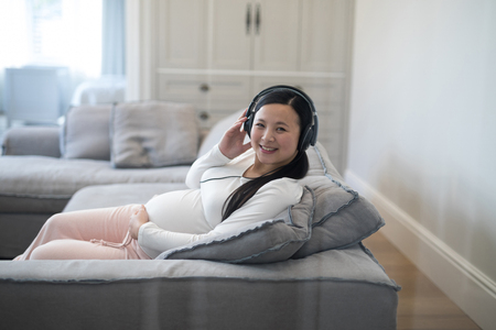 Portrait of pregnant woman listening music on headphonesの写真素材