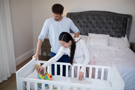 Couple arraigning toys in cot at homeの写真素材