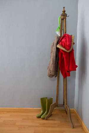 Umbrella, warm clothing and wellington boots arranged on wooden standの写真素材