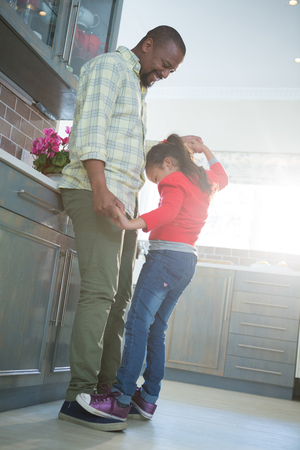 Smiling father and daughter dancing together in kitchenの写真素材