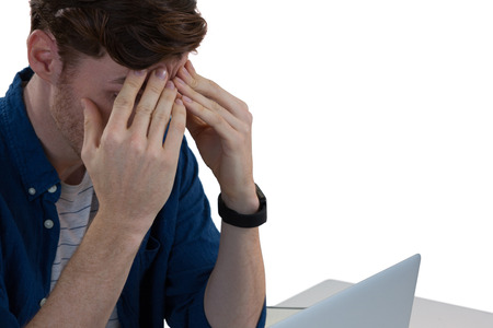 Worried male executive using laptop at deskの写真素材