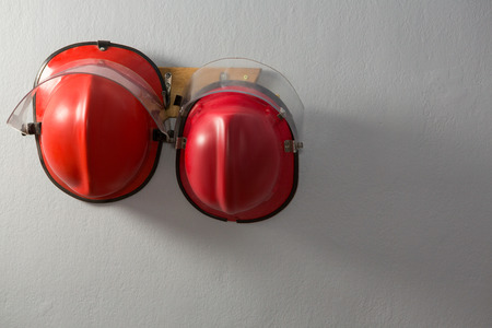 Hard hats hanging on hook against wallの写真素材