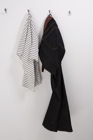 Jeans and shirt hanging on hook against wallの写真素材