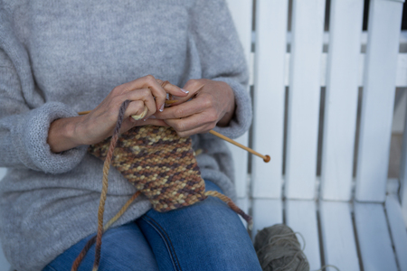 Mid section of woman knitting wool in porchの写真素材