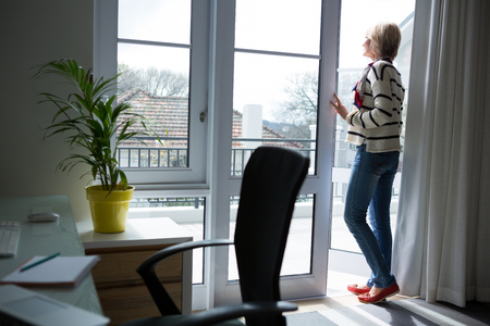 Thoughtful woman standing at homeの写真素材
