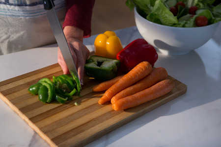Mid section of woman chopping vegetables in kitchenの写真素材