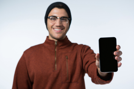 Smiling man in winter cloth holding mobile phone against white backgroundの写真素材
