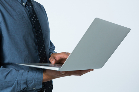 Mid section of executive using laptop against white backgroundの写真素材