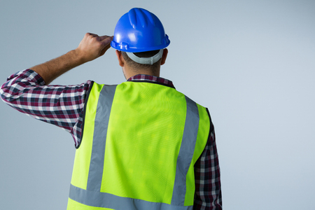 Rear view of male architect standing against white backgroundの写真素材