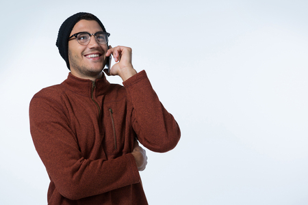 Man in winter cloth talking on mobile phone against white backgroundの写真素材