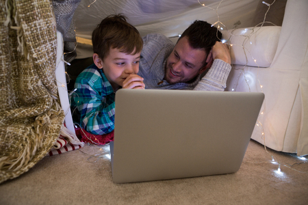 Father and son using laptop in bedroomの写真素材