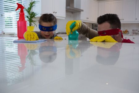 Father and daughter pretending to be superhero while working in kitchenの写真素材