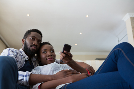 Couple watching television together in living room at homeの写真素材