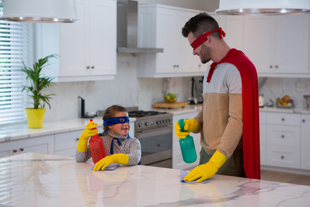 Father and daughter pretending to be superhero while working in kitchenの写真素材