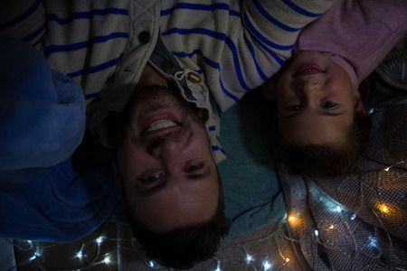 Portrait of happy father and daughter lying in bedroomの写真素材