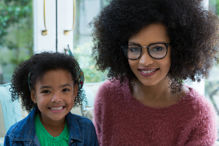 Mother and daughter sitting together in living room at homeの写真素材