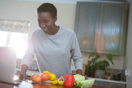 Beautiful woman learning food recipe from laptop in kitchenの写真素材