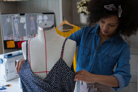 Fashion designer designing a dress on mannequin at homeの写真素材