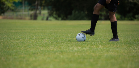 Football player standing with soccer in the ground on a sunny dayの写真素材