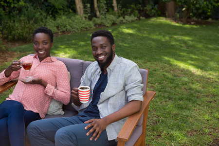 Happy couple having lemon tea and black coffee in gardenの写真素材