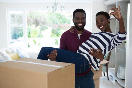 Portrait of man carrying woman while showing house keyの写真素材