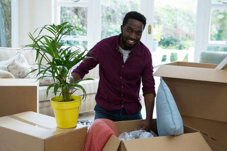 Portrait of happy man unpacking boxes in new houseの写真素材