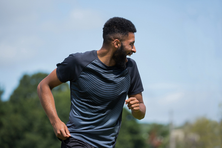Smiling player playing football in the ground on a sunny dayの写真素材