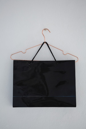 Close-up of shopping bag hanging on wall with hangerの写真素材