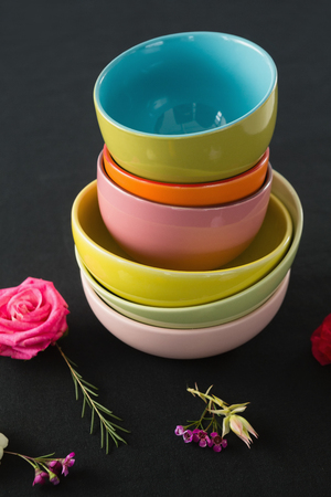 Close-up of bowls and flowers arranged on a black themed tableの写真素材