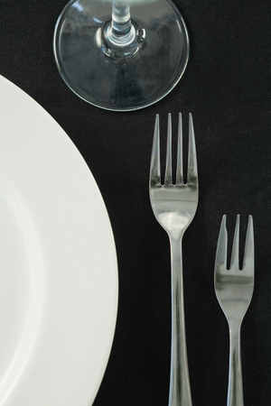 Close-up of dining plates set on black theme tableの写真素材